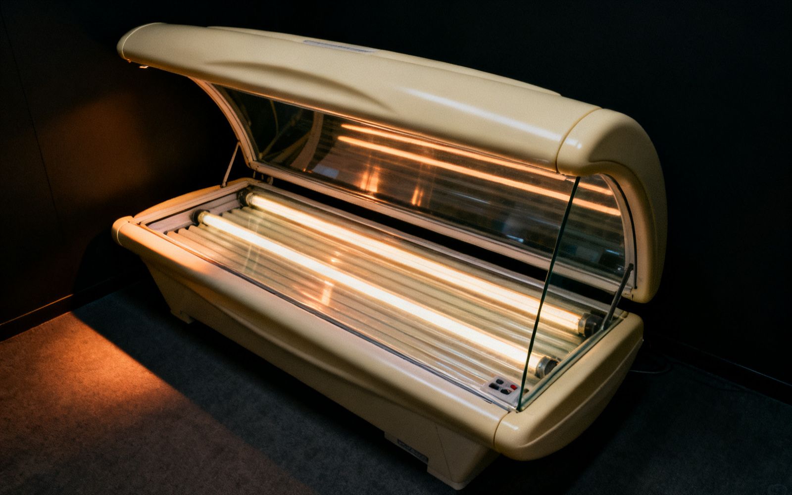 Geöffnete Solariumsliege mit parallel angeordneten UV-Röhren hinter einer Acrylscheibe